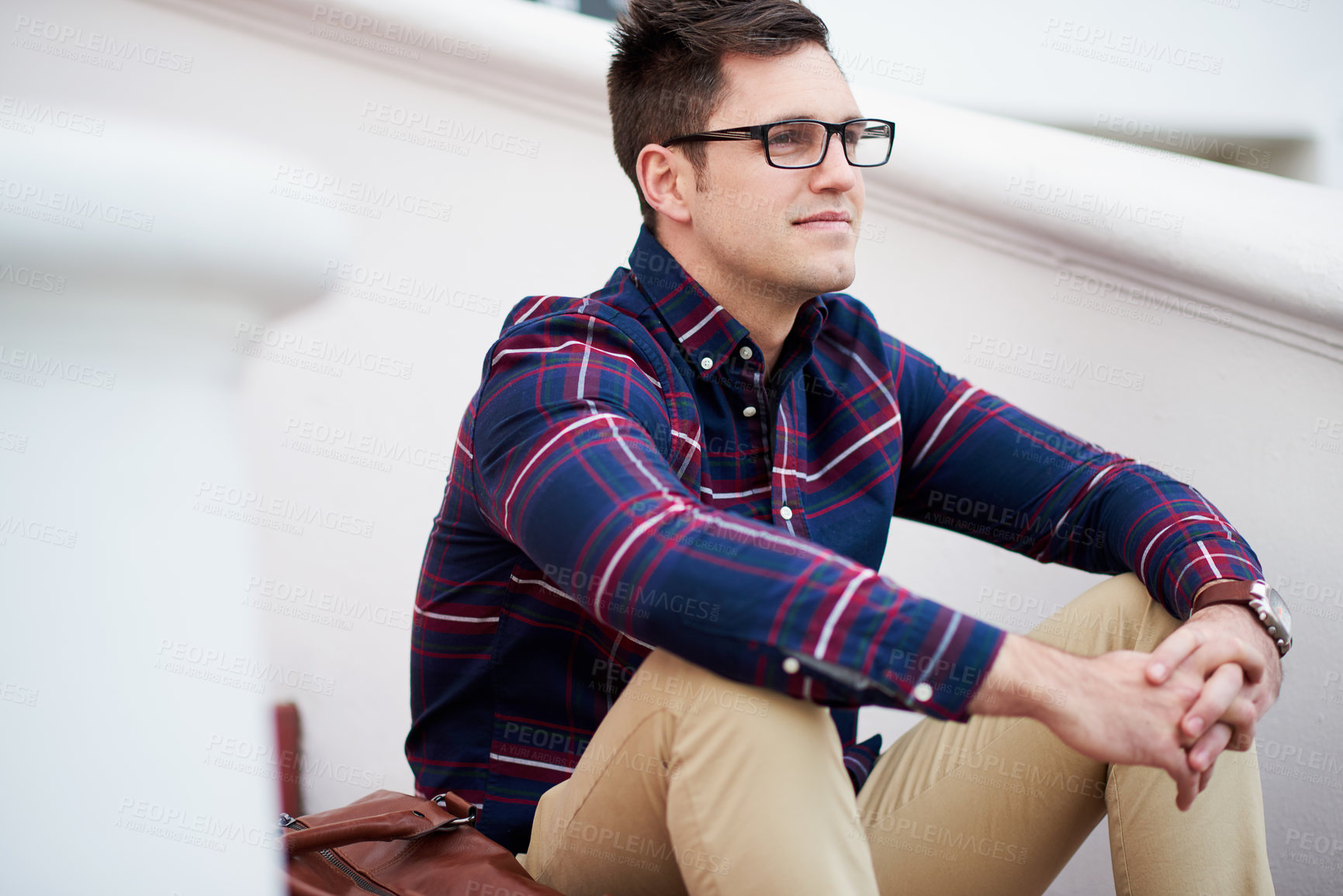 Buy stock photo Shot of a handsome young man sitting on some steps outside