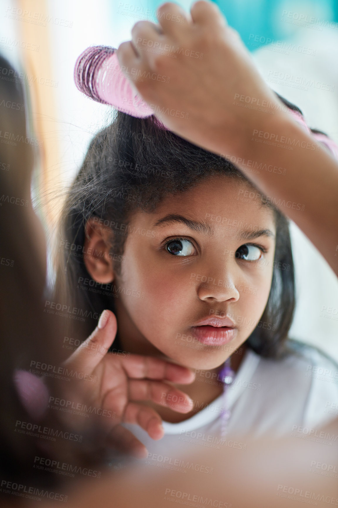 Buy stock photo Shot of a nervous little girl watching as her mother puts curlers in her hair