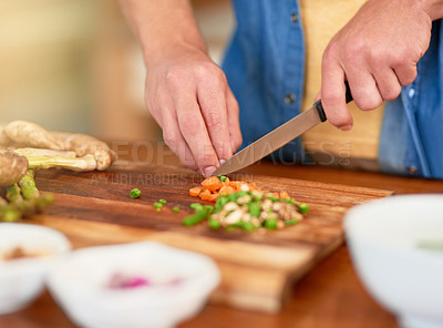 Buy stock photo Closeup shot of a man standing at the kitchen counter chopping up ingredientsfor a meal