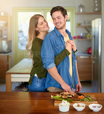 Buy stock photo Shot of an affectionate young couple standing at their kitchen counter chopping up ingredients together for dinner