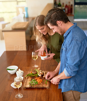 Buy stock photo Shot of a smiling young couple standing at their kitchen counter chopping up ingredients together for dinner