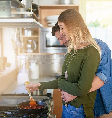 Buy stock photo Shot of an affectionate young couple preparing dinner together at the stove in their kitchen