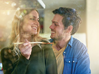 Buy stock photo Smile, woman and couple tasting food in kitchen at house cooking together, celebrate or anniversary with healthy meal. Happy, man and love for dinner with nutrition, diet and bonding for wellness
