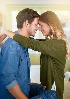 Buy stock photo Shot of an affectionate young couple hugging in their kitchen