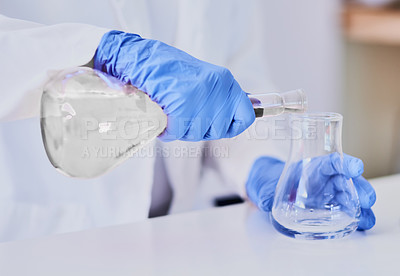 Buy stock photo Cropped shot of a scientist mixing chemicals in beakers while standing in a laboratory