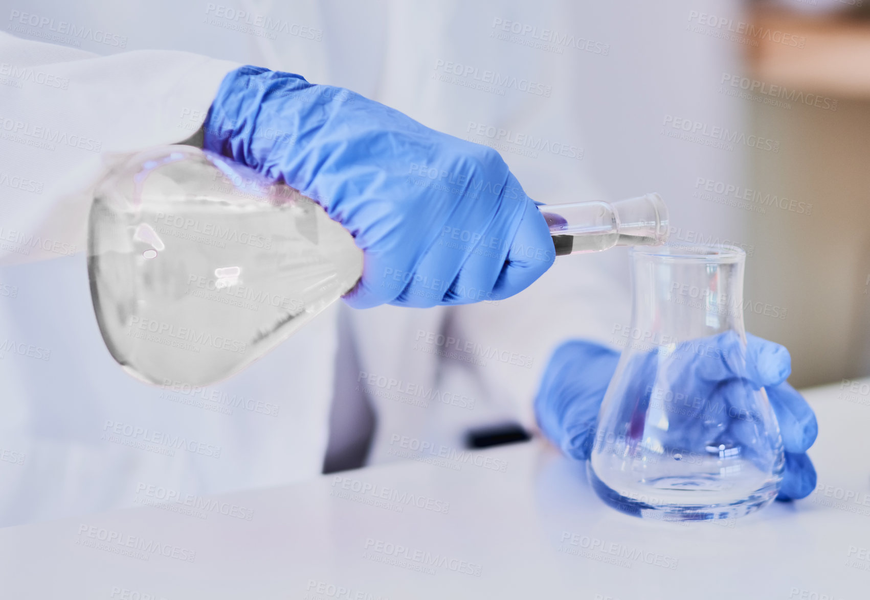Buy stock photo Cropped shot of a scientist mixing chemicals in beakers while standing in a laboratory