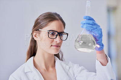Buy stock photo Shot of a scientist examining a beaker of liquid while standing in a laboratory