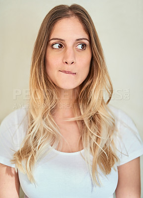 Buy stock photo Cropped shot of an attractive young woman biting her lip in studio