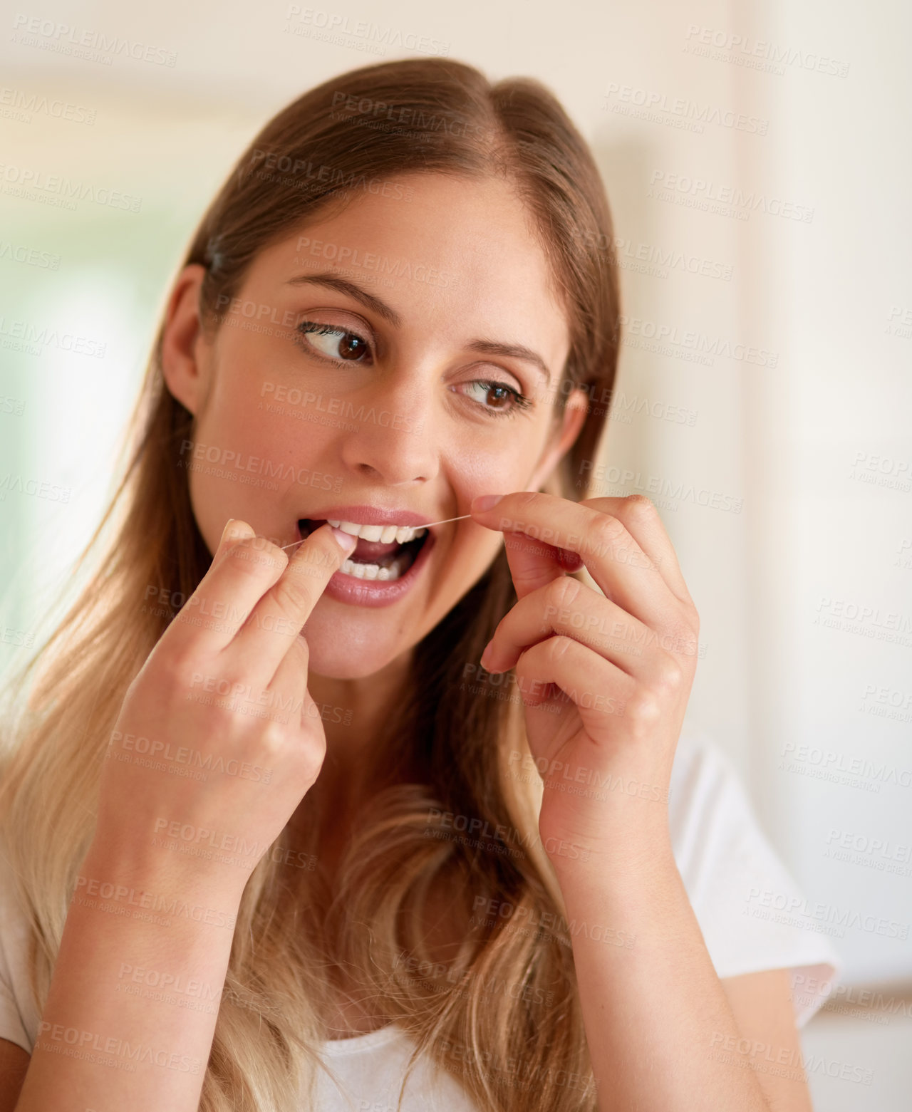 Buy stock photo Cropped shot of a young woman flossing her teeth at home