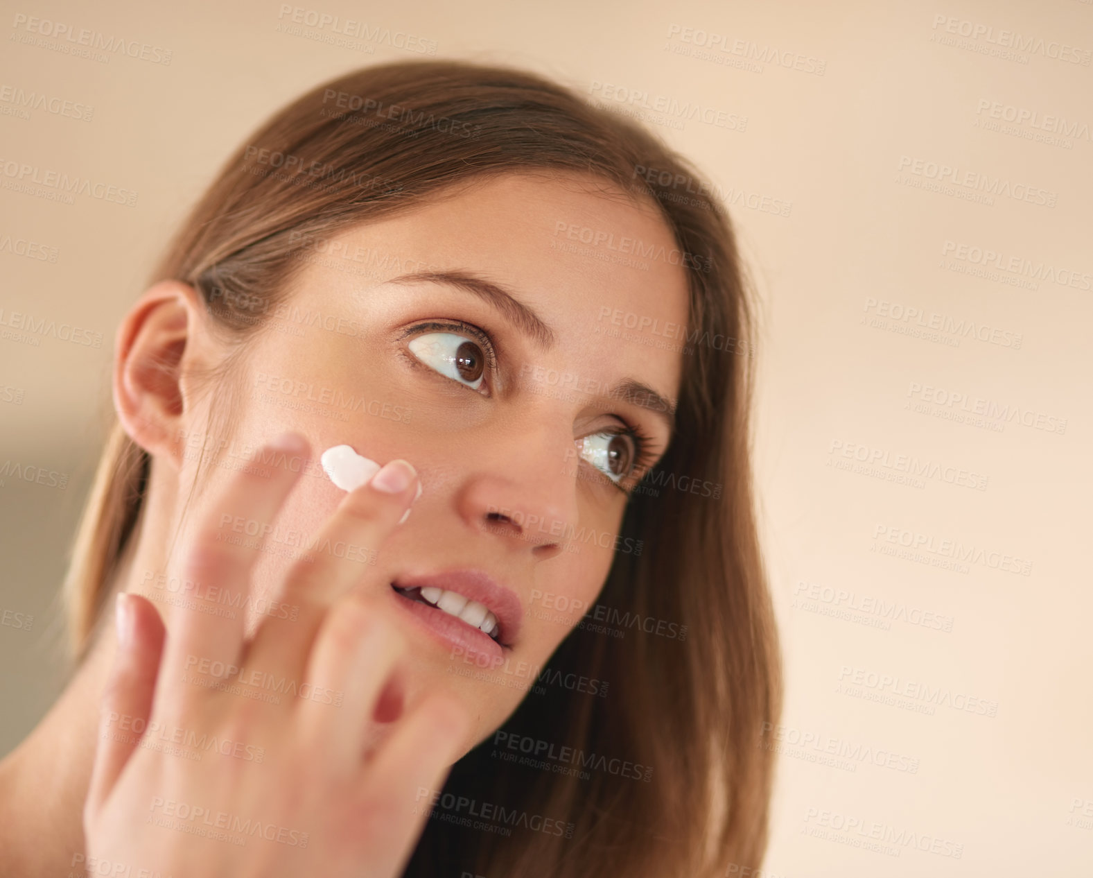 Buy stock photo Cropped shot of a young woman applying moisturiser to her face