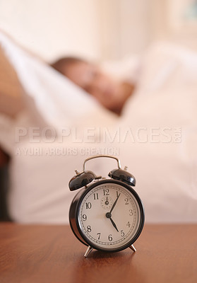 Buy stock photo Cropped shot of a young woman sleeping in bed with an alarm clock beside her