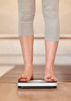 Buy stock photo Closeup shot of a young woman weighing herself on a scale at home
