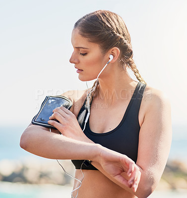 Buy stock photo Shot of an attractive young woman setting up a playlist for her morning run