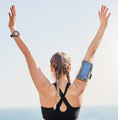 Buy stock photo Rearview shot of an attractive young woman standing with her arms raised after her morning run