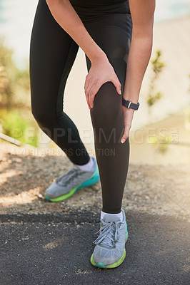Buy stock photo Shot of an unrecognizable young woman holding her knee in pain during her morning run