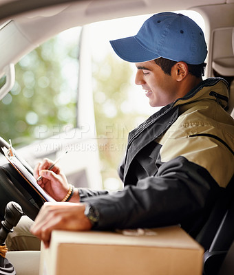 Buy stock photo Cropped shot of a delivery man writing on a clipboard while sitting in his van