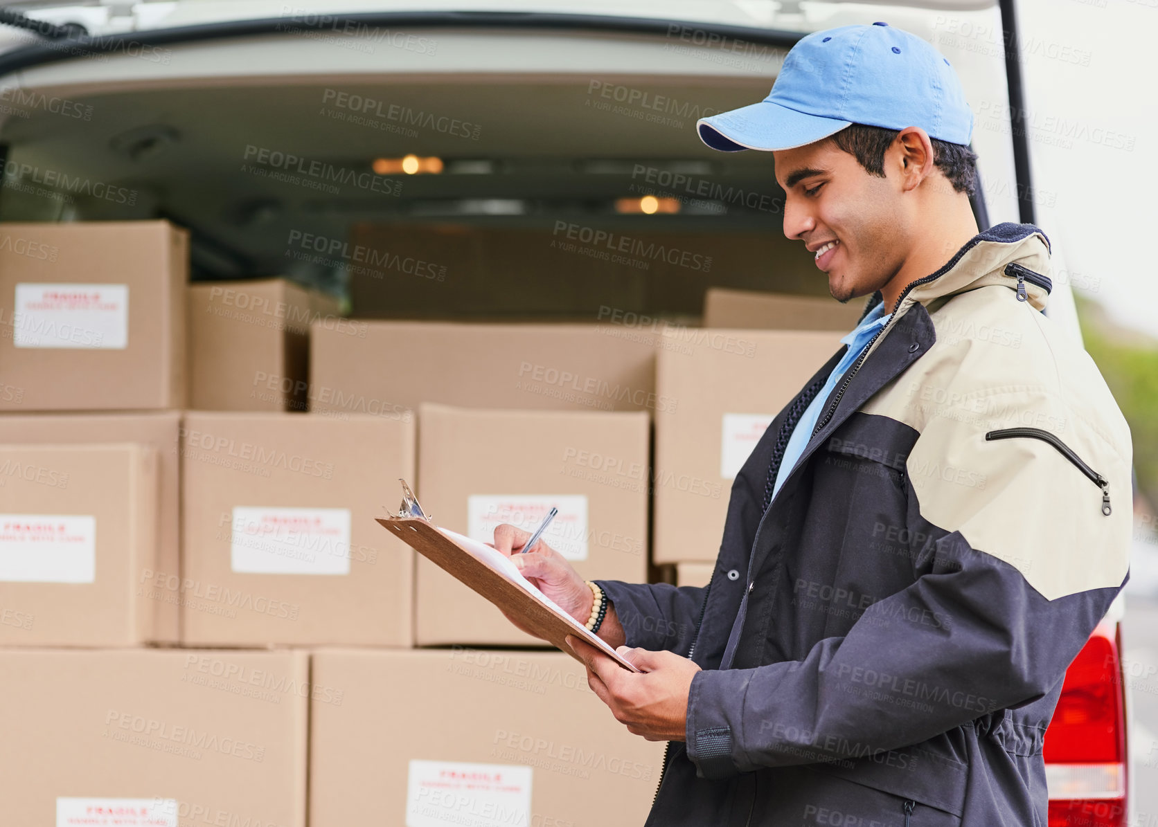 Buy stock photo Cropped shot of a delivery man writing on a clipboard while standing next to a van full of boxes