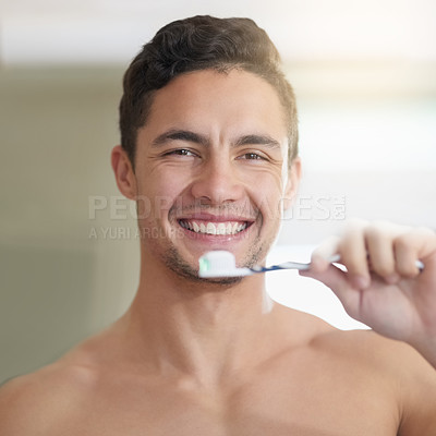 Buy stock photo Shot of a handsome young man brushing his teeth at home
