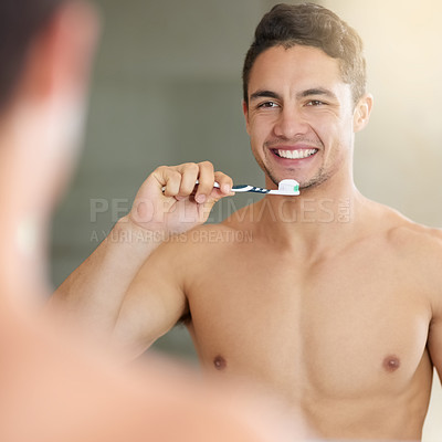 Buy stock photo Shot of a handsome young man brushing his teeth at home