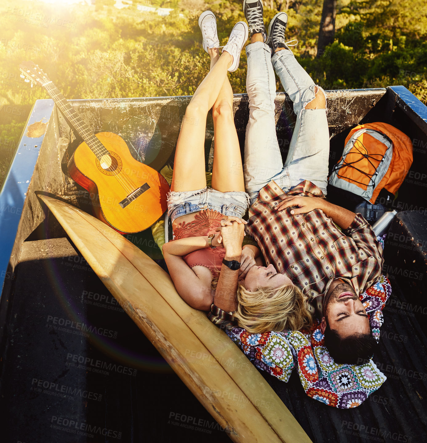 Buy stock photo Shot of a young couple lying at the back of a pickup truck to relax after a long drive