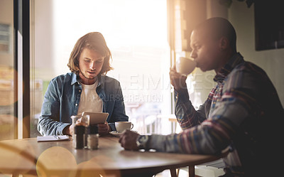 Buy stock photo Shot of  two friends using a tablet while having coffee in a coffee shop