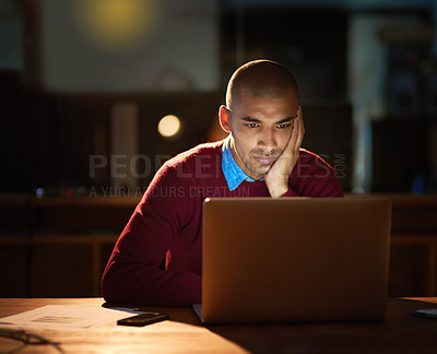 Buy stock photo Sho of a young man looking bored while working late in his office