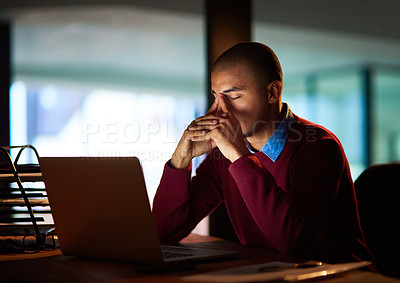 Buy stock photo Shot of a young man looking stressed out while working late in his office