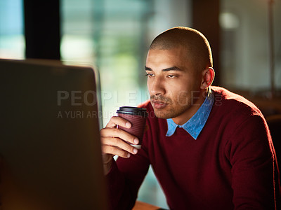 Buy stock photo Shot of a young man drinking coffee while working late in an office