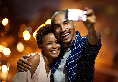 Buy stock photo Cropped shot of an affectionate young couple taking selfies while out on a date in the city