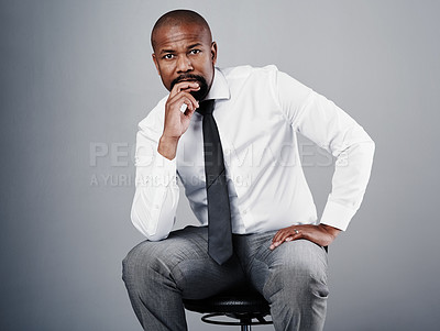 Buy stock photo Studio portrait of a corporate businessman sitting on a chair against a grey background