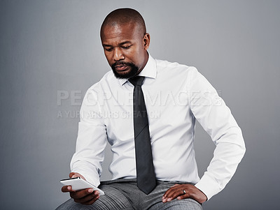 Buy stock photo Studio shot of a corporate businessman texting on his cellphone against a grey background