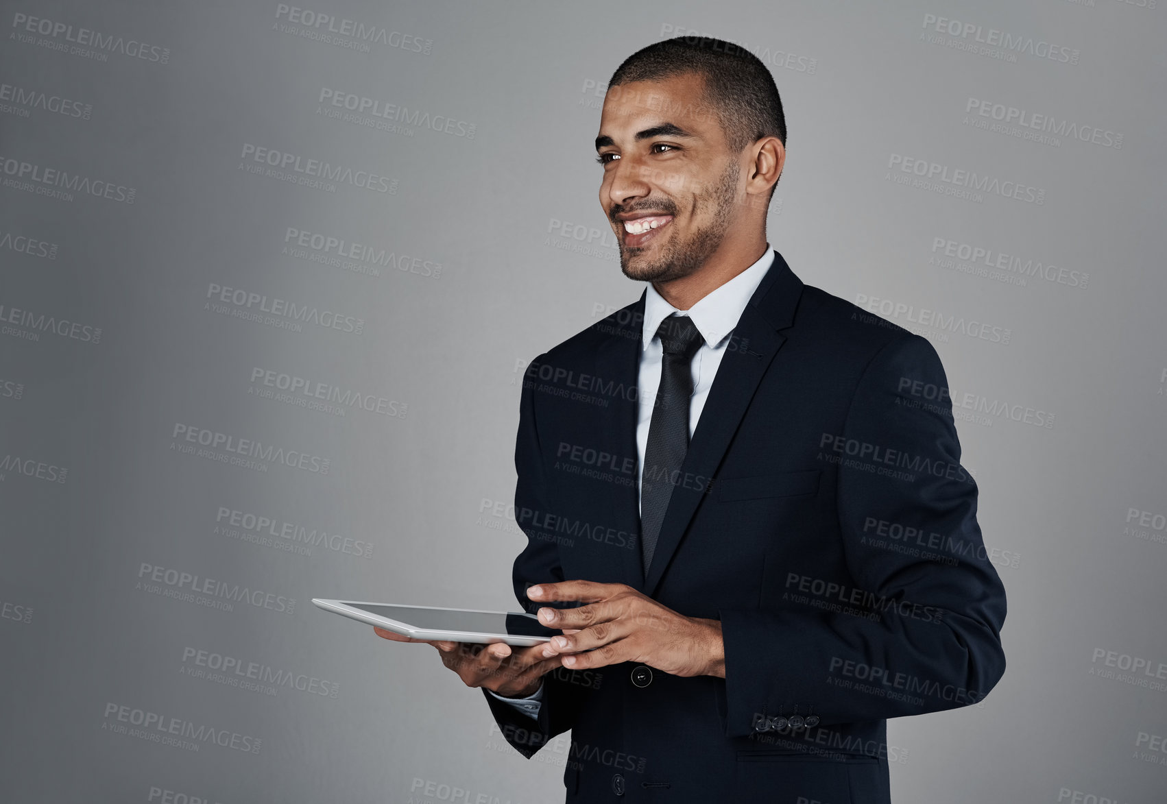 Buy stock photo Studio shot of a corporate businessman using a digital tablet against a grey background