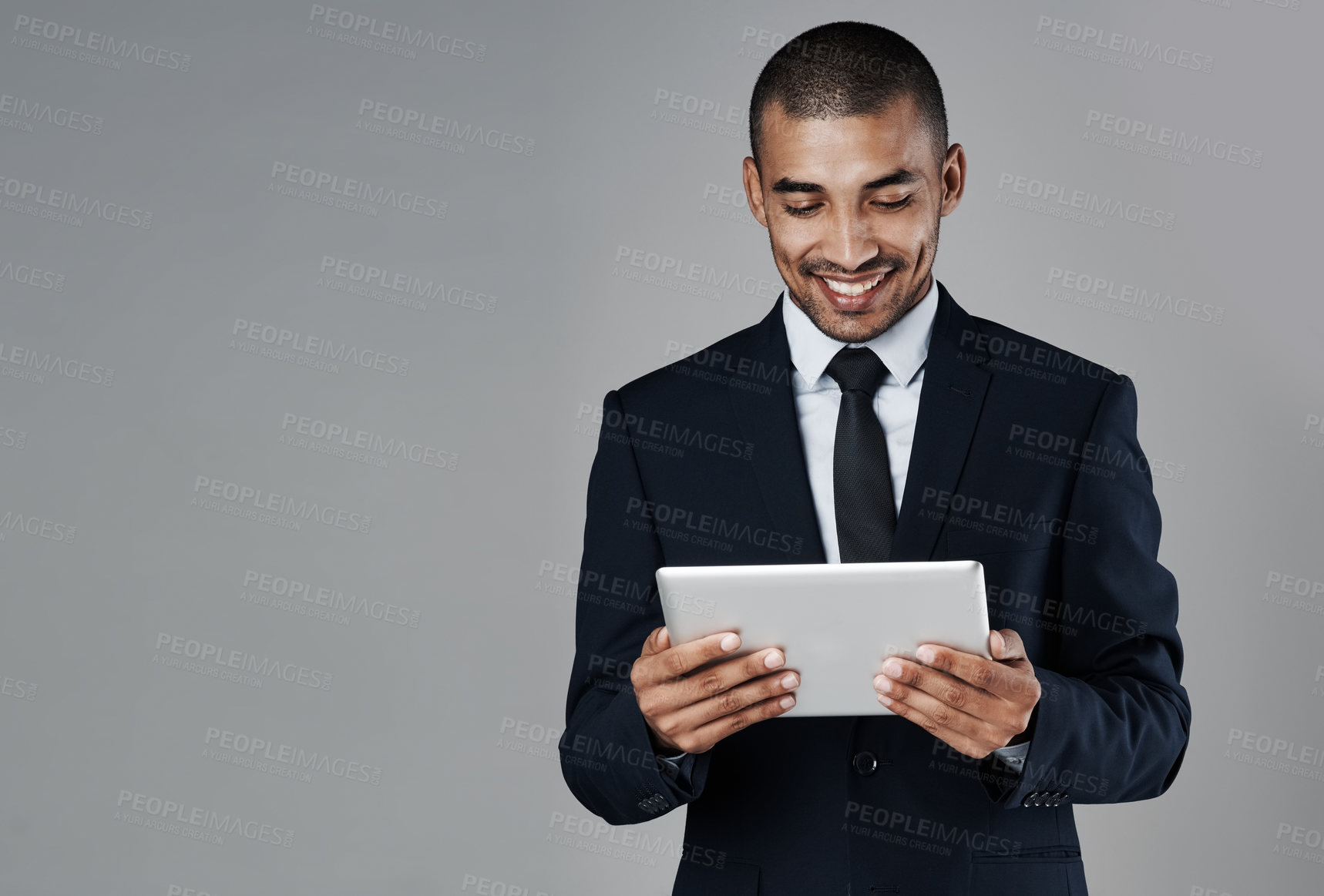 Buy stock photo Studio shot of a corporate businessman using a digital tablet against a grey background
