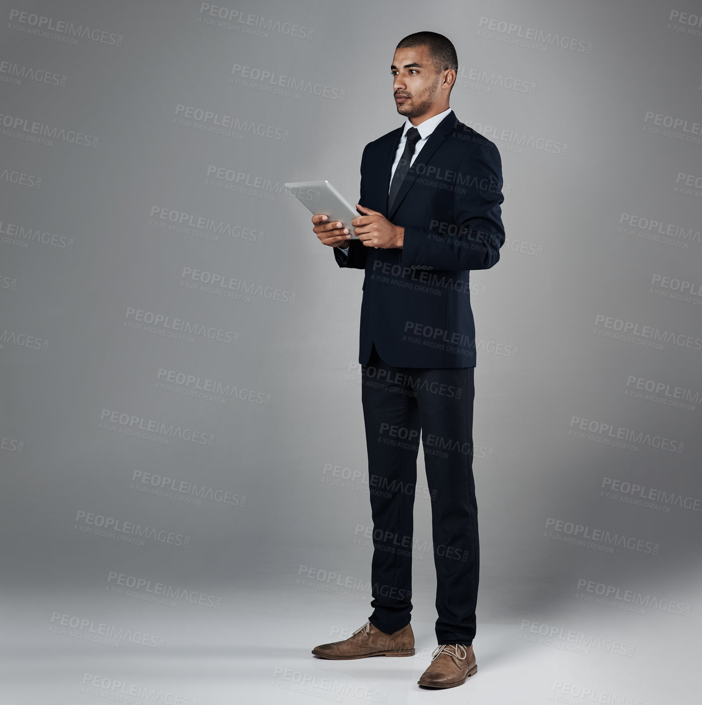 Buy stock photo Studio shot of a corporate businessman using a digital tablet against a grey background