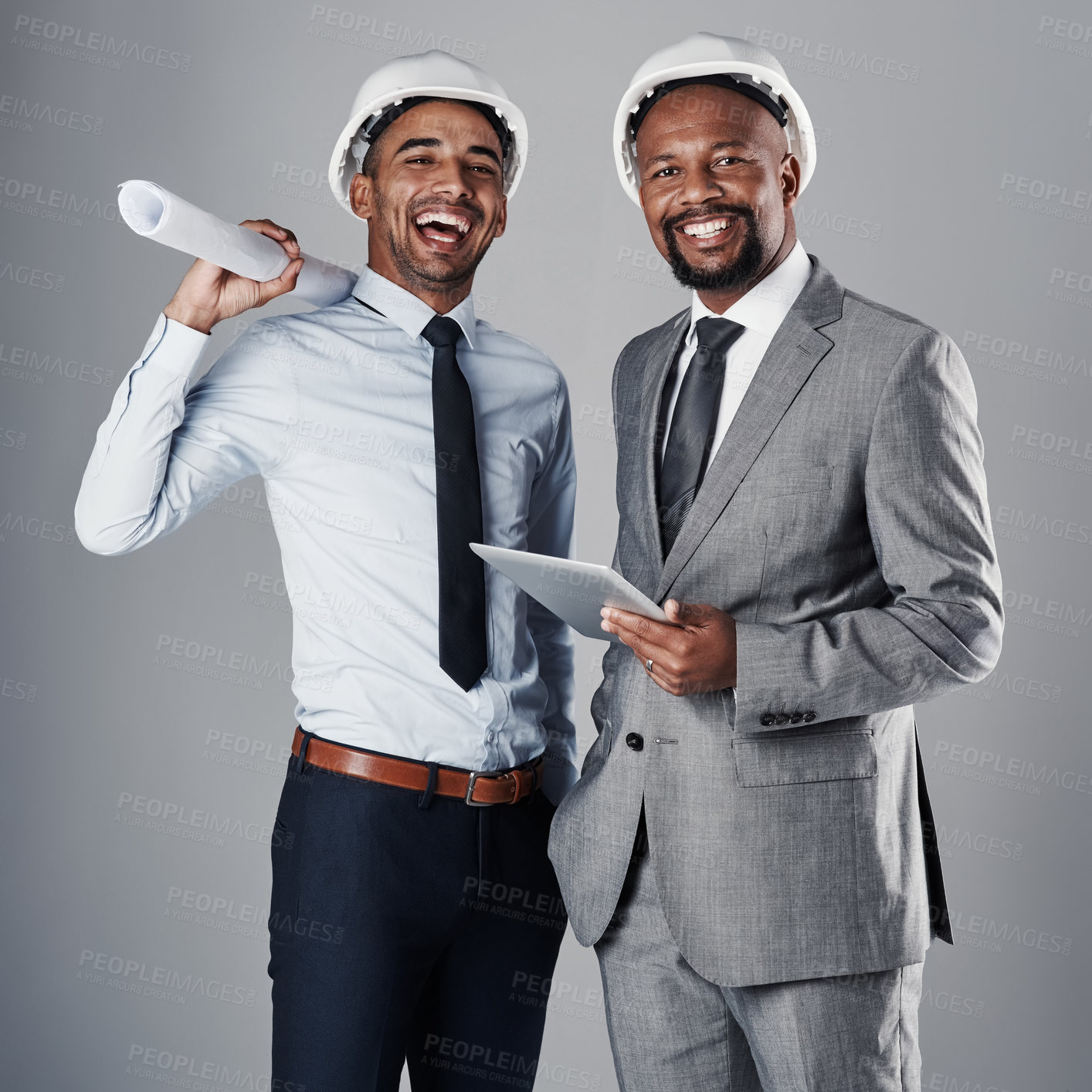 Buy stock photo Shot of two civil engineers discussing building plans while standing in the studio