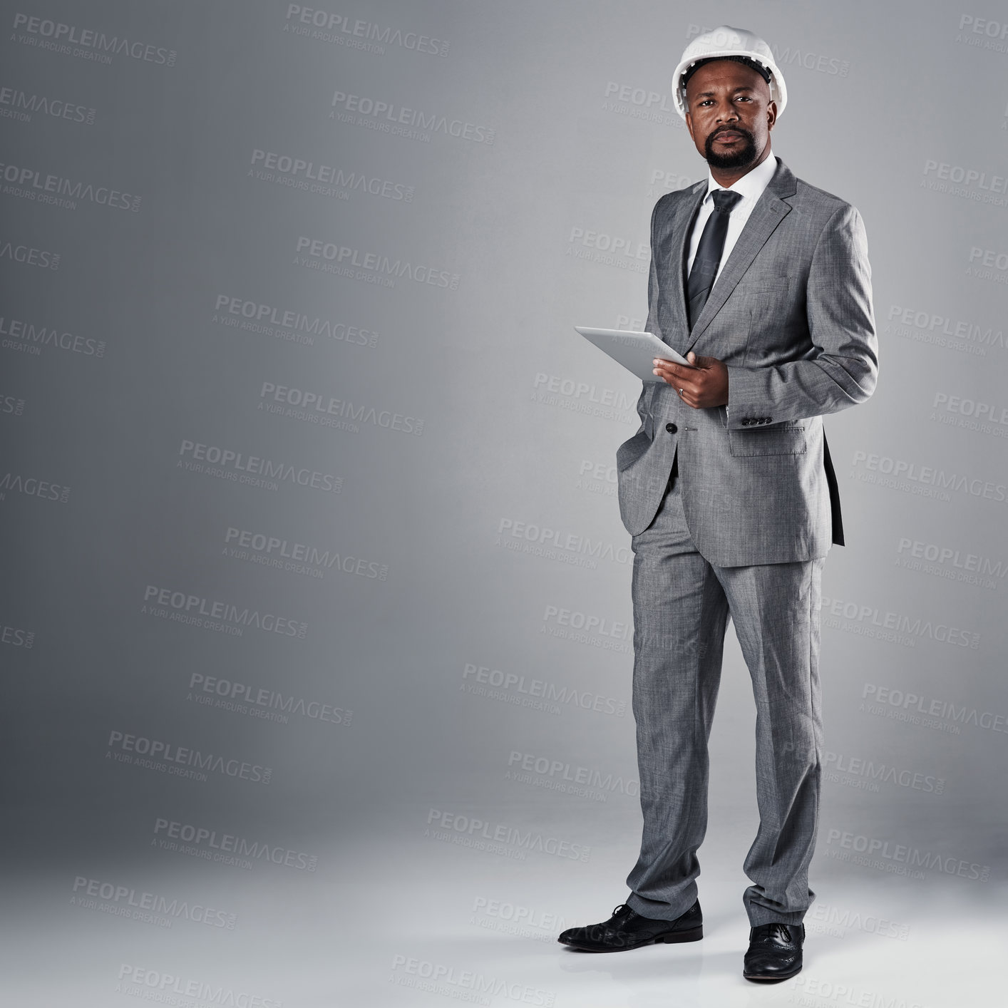 Buy stock photo Man, architect and tablet in studio portrait in suit, helmet and mock up space by gray background. African person, engineering and touchscreen with application, review and floor plan in Nigeria