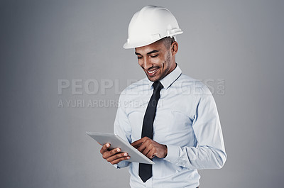 Buy stock photo Shot of a well-dressed civil engineer using his tablet while standing in the studio