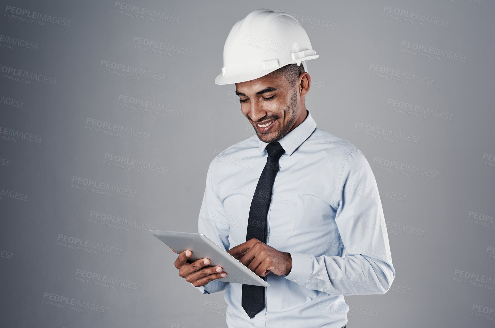 Buy stock photo Engineer, tablet and happy with digital research and online blueprint of builder in studio. Contractor, planning and helmet of Indian male professional with web scroll, tech and grey background