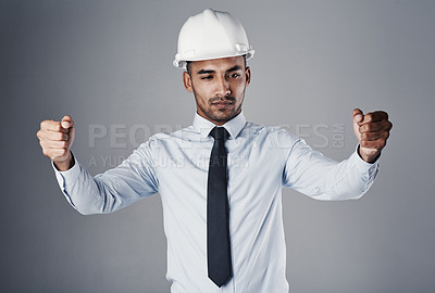 Buy stock photo Shot of a well-dressed civil engineer pretending to hold open blueprints while standing in the studio