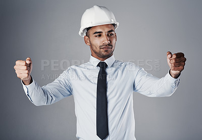Buy stock photo Shot of a well-dressed civil engineer pretending to hold open blueprints while standing in the studio