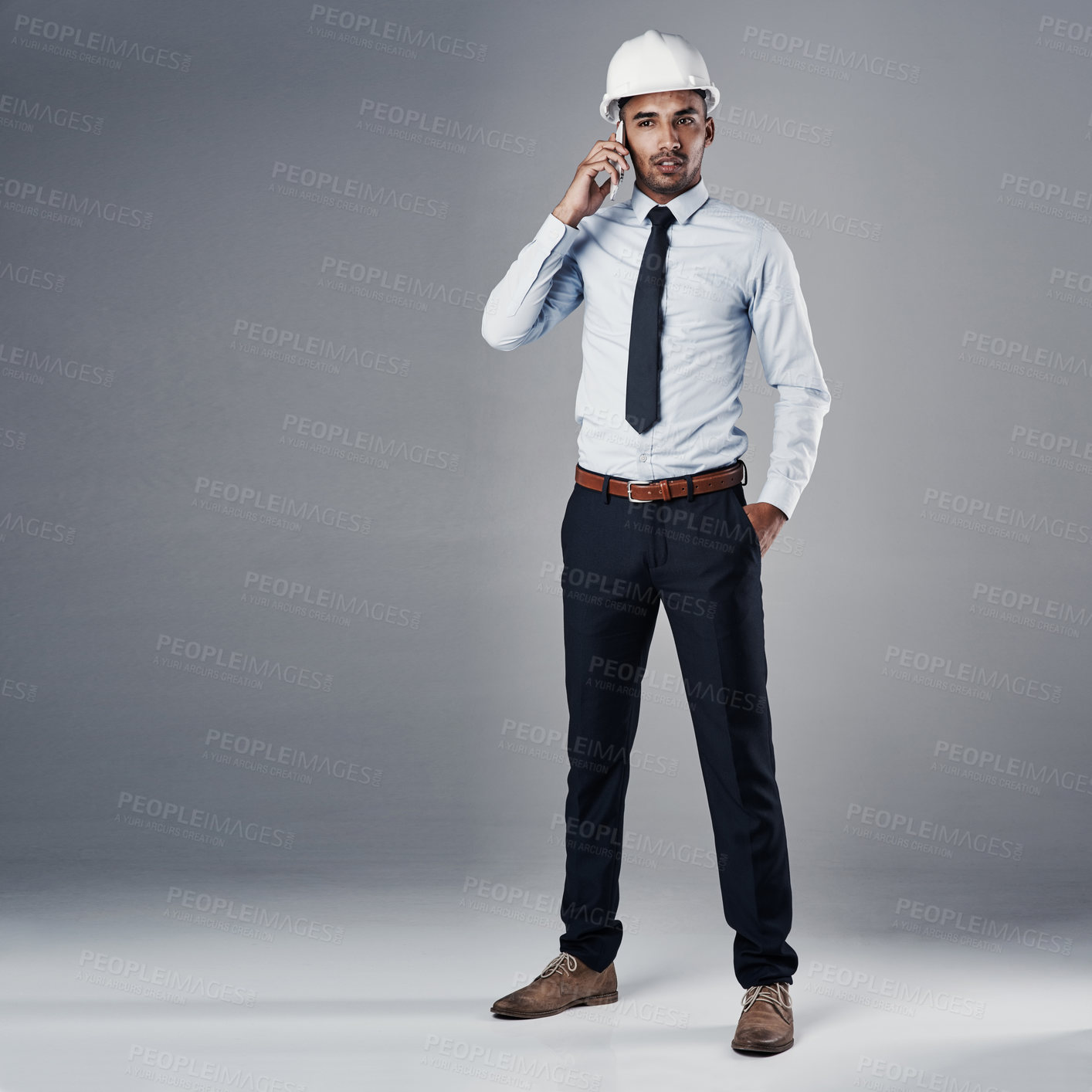 Buy stock photo Architect, helmet and phone call in studio for construction, communication and renovation update. Engineering, man and mobile on gray background for conversation, research and architecture project