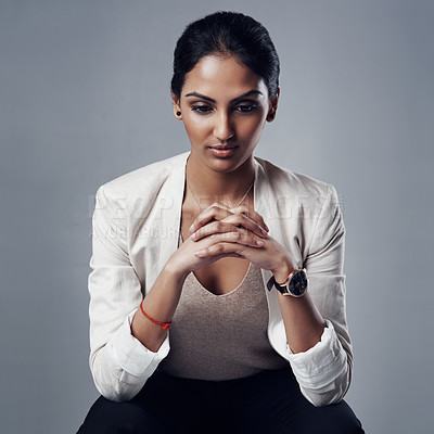 Buy stock photo Studio shot of a young businesswoman looking pensive against a gray background