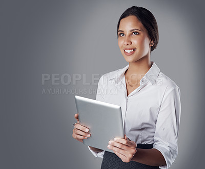 Buy stock photo Studio shot of a young businesswoman using a digital tablet against a gray background