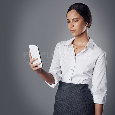 Buy stock photo Studio shot of a young businesswoman using a phone against a gray background