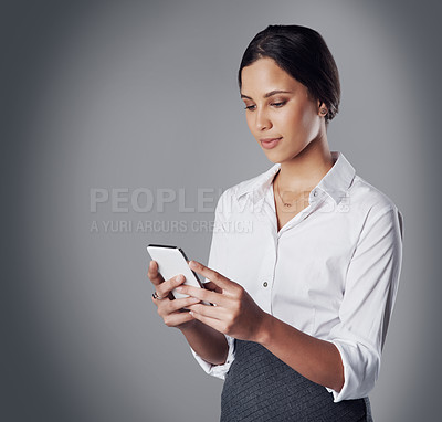 Buy stock photo Studio shot of a young businesswoman using a phone against a gray background