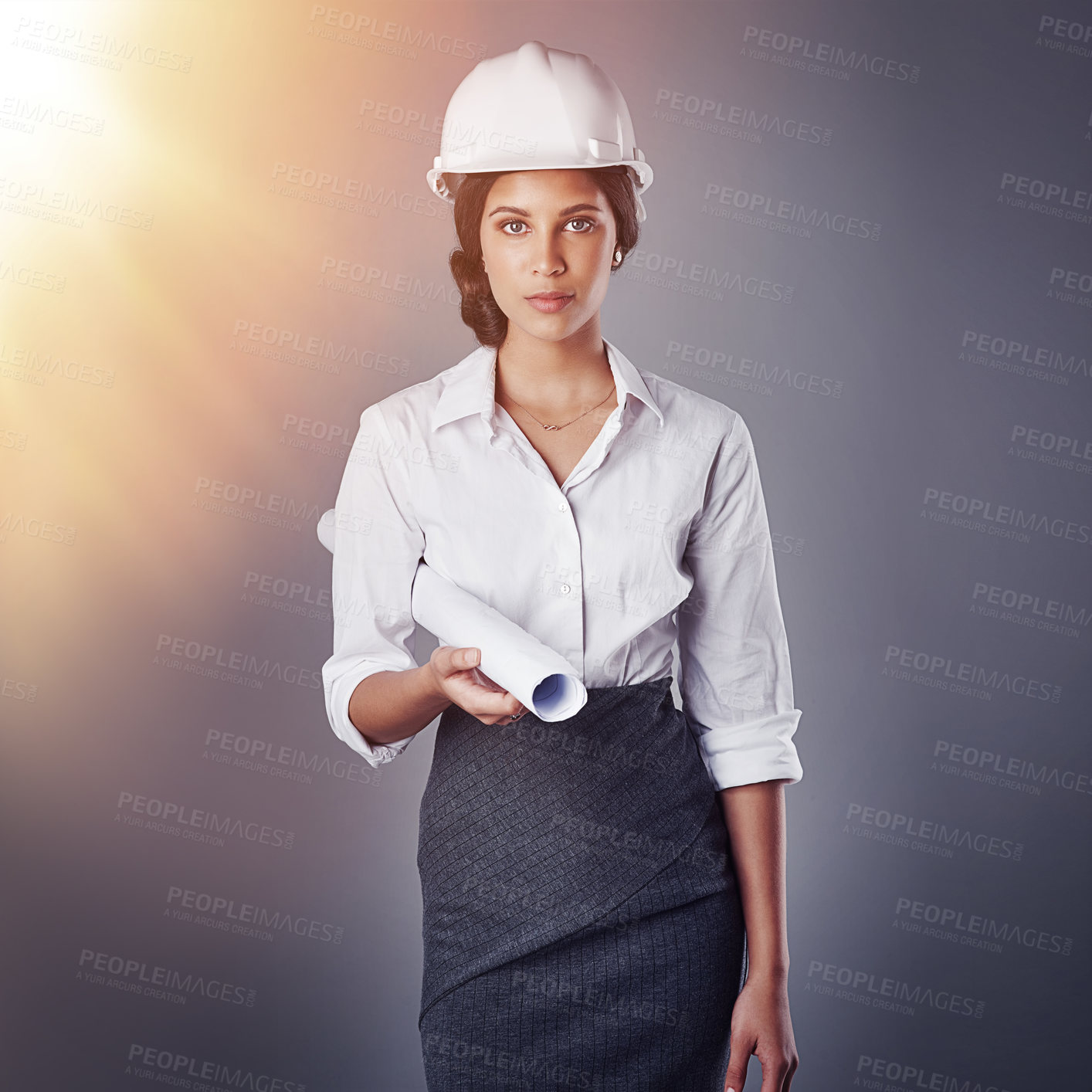 Buy stock photo Portrait of a well-dressed civil engineer posing while holding blueprints in the studio