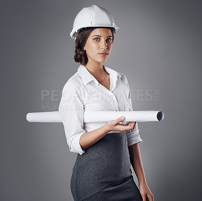 Buy stock photo Portrait of a well-dressed civil engineer posing while holding blueprints in the studio