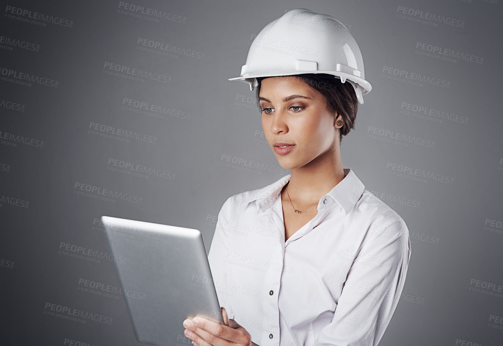 Buy stock photo Shot of a well-dressed civil engineer using her tablet while standing in the studio