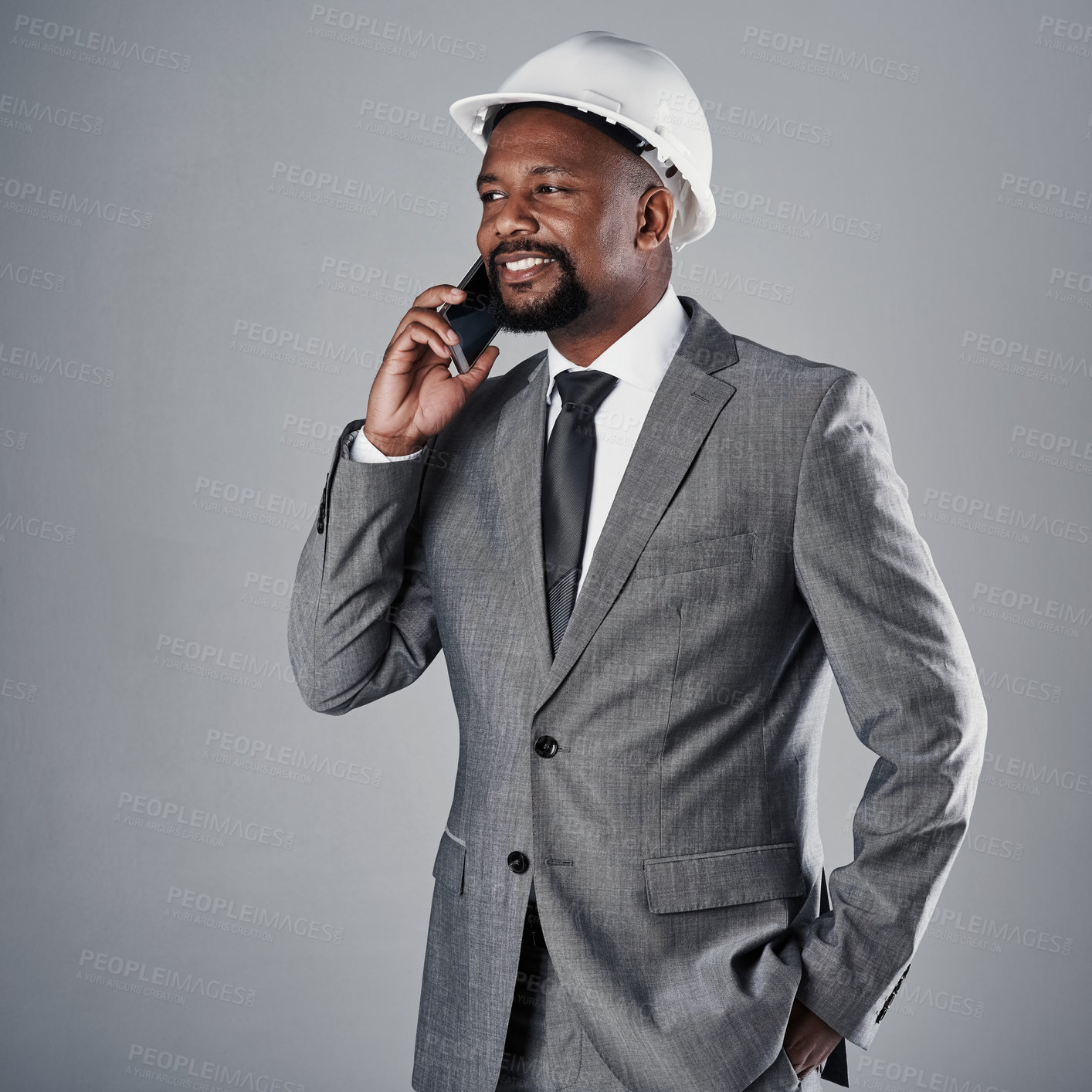 Buy stock photo Shot of a well-dressed civil engineer using his cellphone while standing in the studio