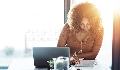 Buy stock photo Shot of a young woman using a digital tablet at her work desk